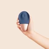 white hand holds a rose gold and slate blue sex toy showing the tapping mechanism