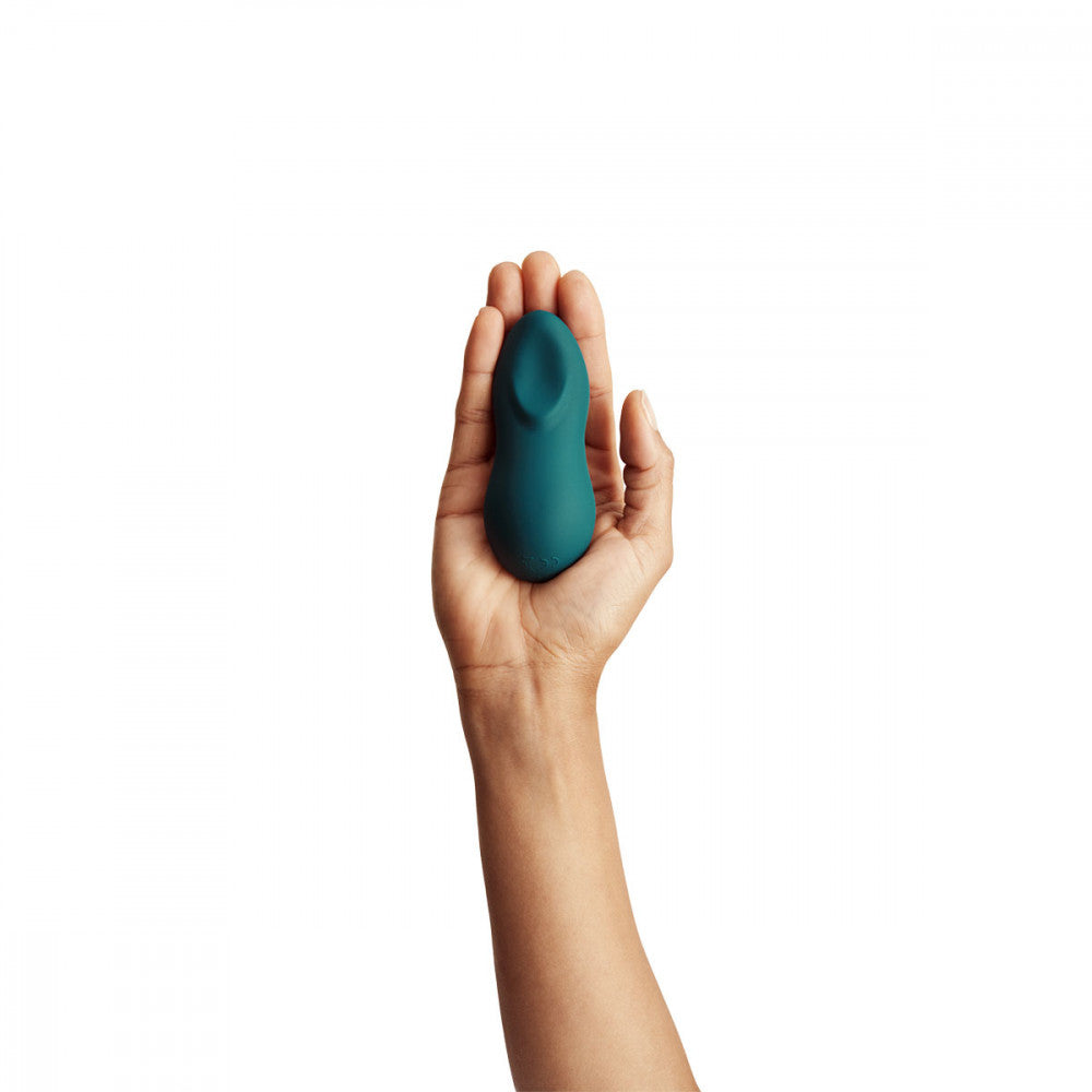 a white hand palms the teal green silicone sex toy to how that it is smaller than an average palm