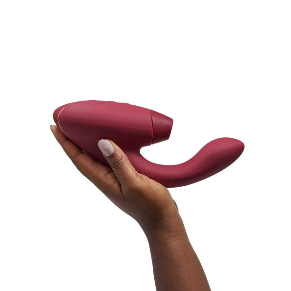 brown hand shows the size of the womanizer duo 2 rabbit sex toy that takes up the whole palm and extends several inches past it with the vibrating arm. it is a large toy